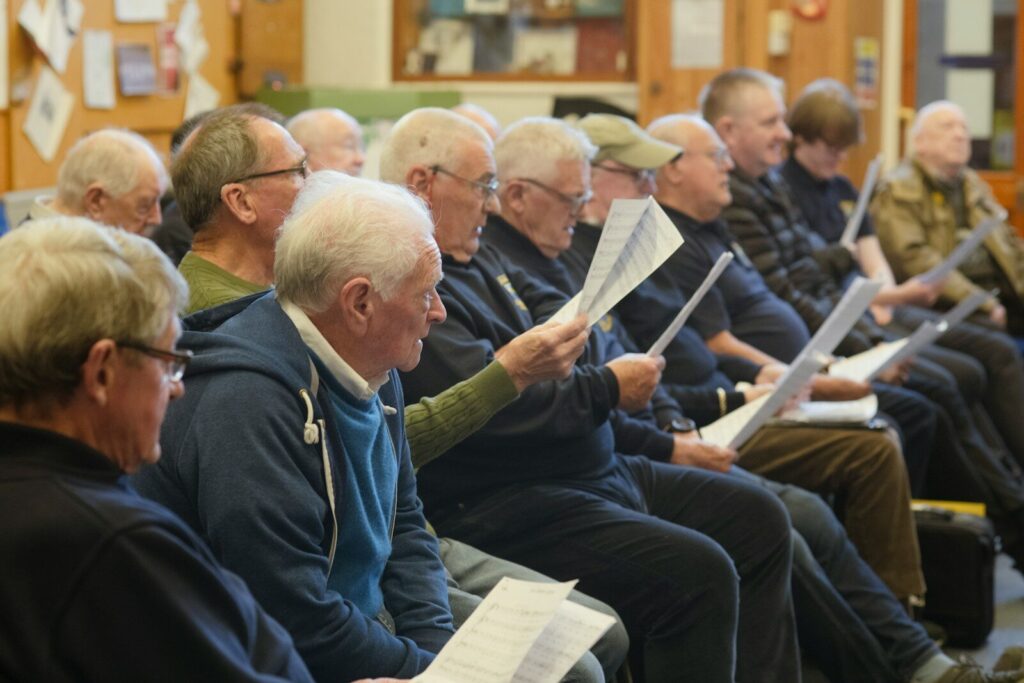 A group of older men reading notes in a room