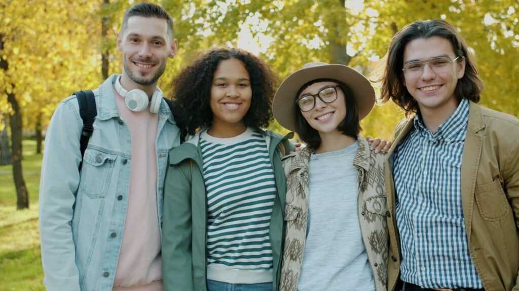 Four friends smiling in a park during autumn